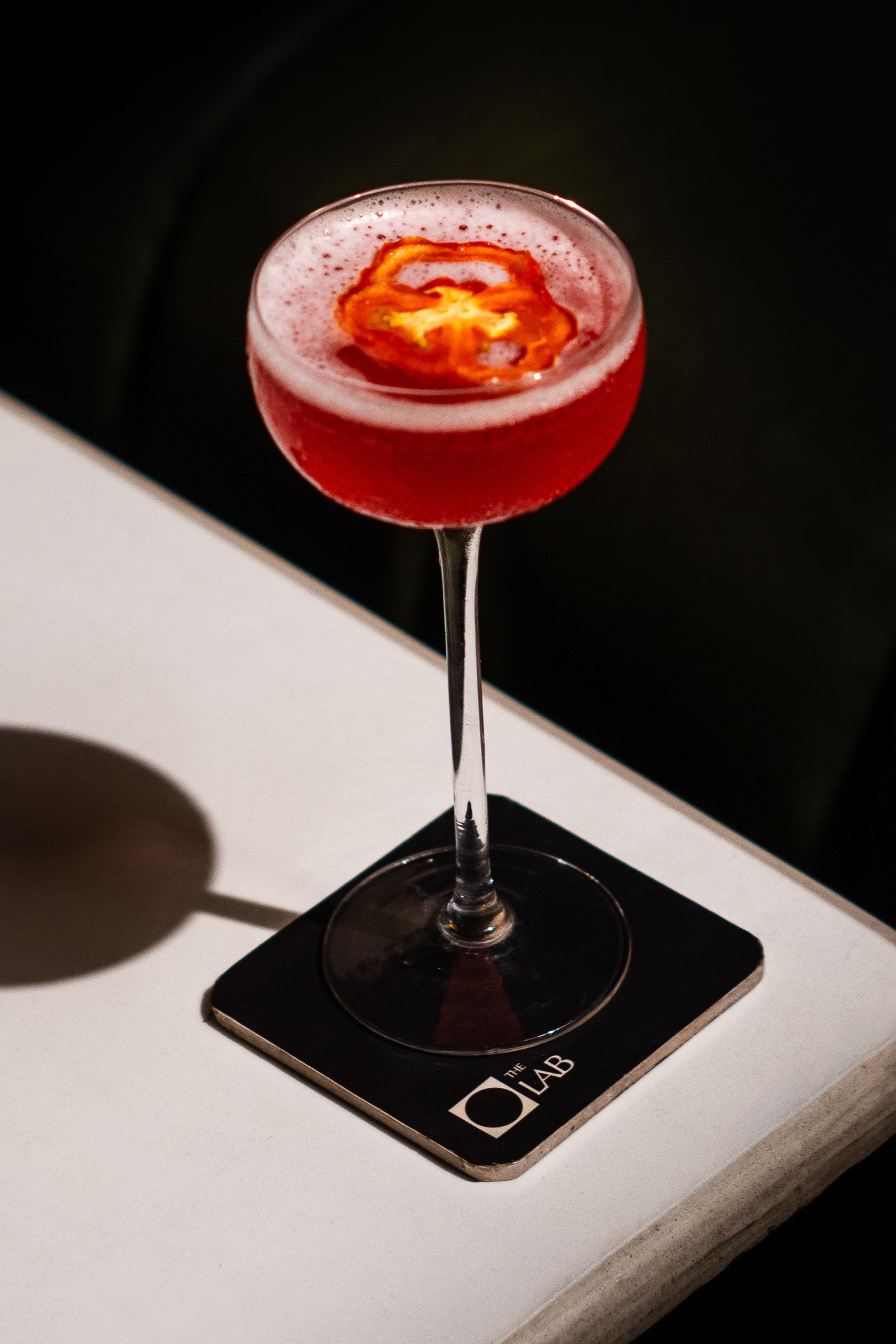 A red cocktail on a The Lab coaster